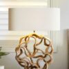 Sculptural table lamp with intricate wooden base.